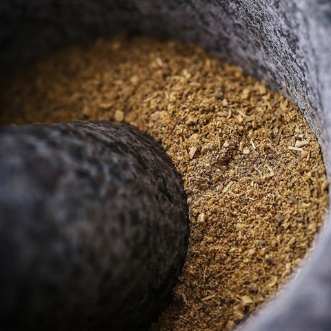 Close-up of ground spices inside black granite mortar with pestle