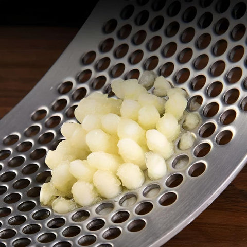 Close-up of minced garlic inside stainless steel garlic press holes