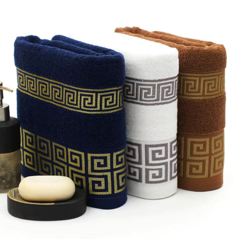Folded cotton towels in brown, navy, green, black, and gray with Greek pattern