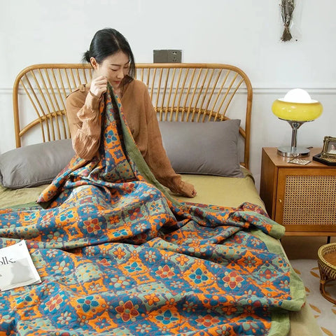 Woman arranging a colorful floral blanket on a bed in a bedroom setting.