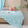 Soft, breathable blue bed blanket draped over beige bed with matching pillows and a light, airy setting
