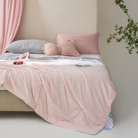 Soft, breathable pink bed blanket draped over beige bed with matching pillows and a light, airy setting