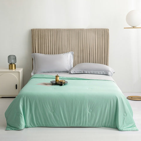 Water green Cool Touch Quilt neatly styled on bed with gray pillows