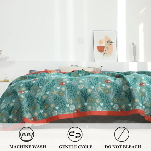 Close-up of Coral Reef Boho Cotton Throw Blanket showing machine washable, gentle cycle, and do not bleach icons with bedroom background.