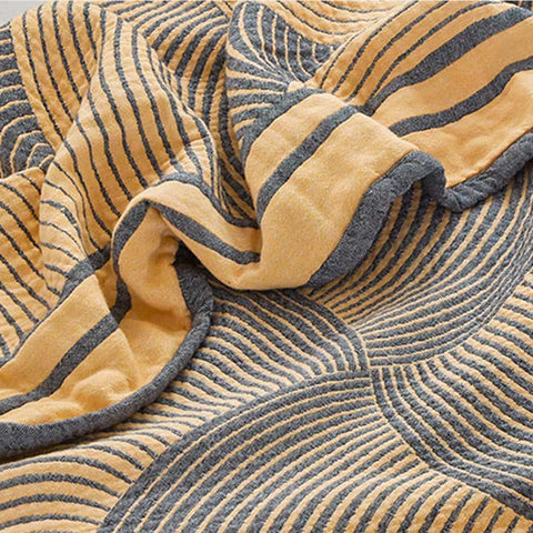 Textured blanket quilt with wavy pattern in gold and gray on a matching fabric background