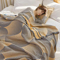 Yellow and gray patterned quilt on white bed