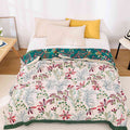 Full view of Alba floral gauze blanket spread on bed with yellow pillows

