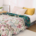 Floral cotton summer gauze blanket styled on queen bed with decorative pillows