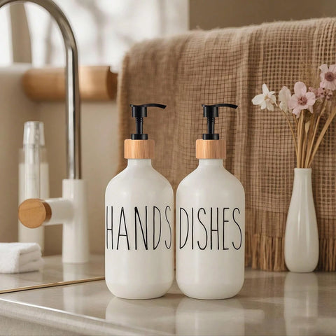 Two white soap dispensers labeled 'HANDS' and 'DISHES' on a bathroom counter.