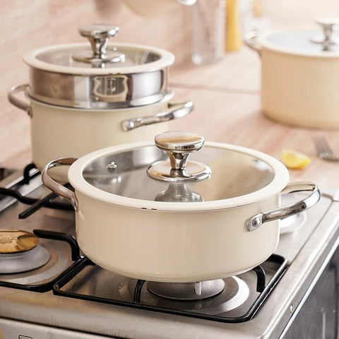 Cream nonstick cookware with steamer basket on gas stove