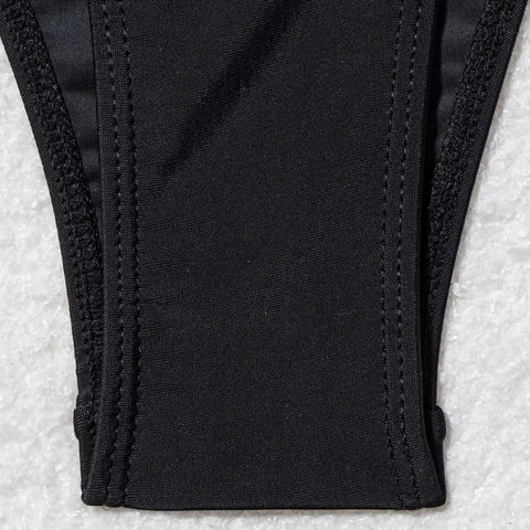 Close-up of bikini bottom with gold bead side ties – black stretch fabric