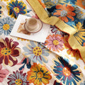 Close-up of Daisy Flower Cotton Blanket showing fabric, edges, coffee cup, and magazine on floral pattern