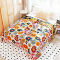 Top view of full spread Daisy Flower Cotton Blanket on a bed with cup of tea and tray, pictures, window, carpet