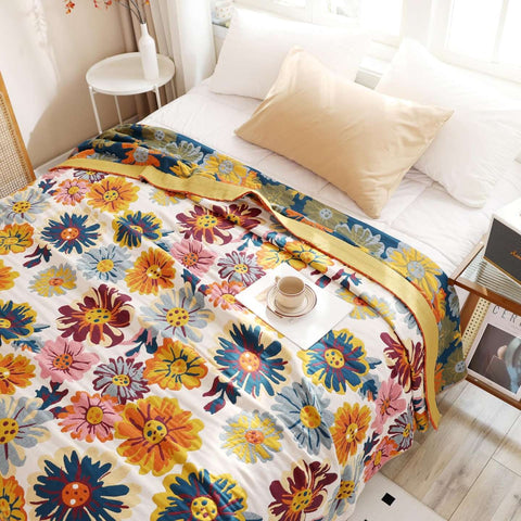 Top view of full spread Daisy Flower Cotton Blanket on a bed with cup of tea and tray, magazine, pillows, pictures