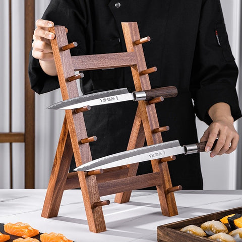 Person holding two knives on a wooden stand with a blurred background
