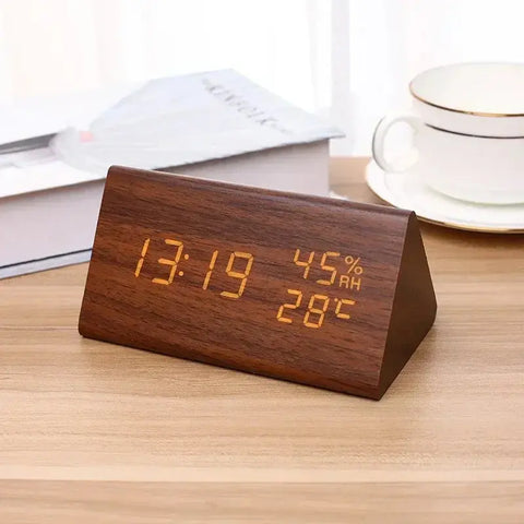 Wooden digital clock displaying time, temperature, and humidity on a wooden surface.