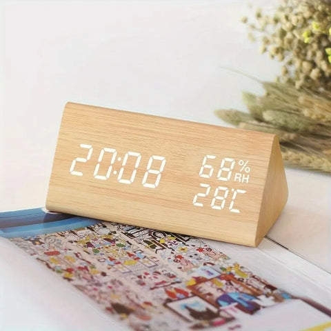Wooden digital clock with LED display on a surface with a blurred background