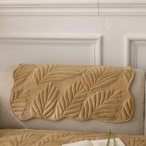Beige quilted leaf-patterned mat on a beige sofa against a light-colored wall.