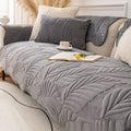 Dark gray plush non-slip sofa cover with pillows on modern couch