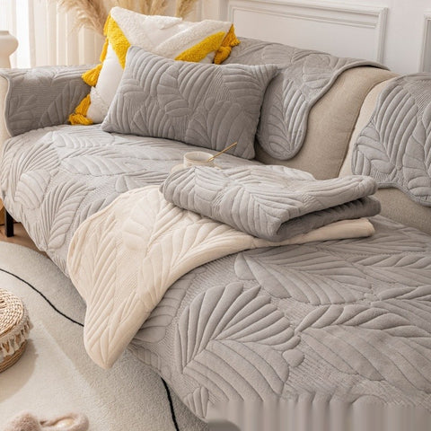 Light gray quilted sofa cover with leaf design on cozy 3-seater