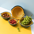 Set of yellow and blue colanders with fruits on a yellow surface