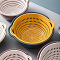 Set of colorful colanders on a gray surface