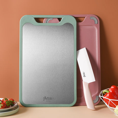 Two cutting boards, one green and one pink, with a knife on a beige surface against a brown background.