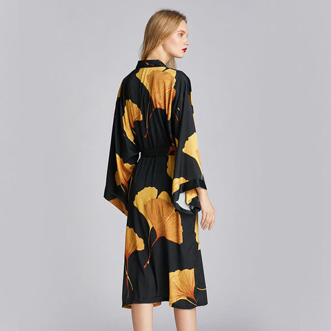Elegant satin kimono robe in black with bold golden ginkgo leaf design, wide sleeves, and adjustable belt—luxury homewear for lounging or special occasions.