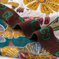 Close-up of a colorful cotton blanket fabric with intricate patterns and brown ribbon.