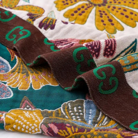 Close-up of a colorful cotton blanket fabric with intricate patterns and brown ribbon.