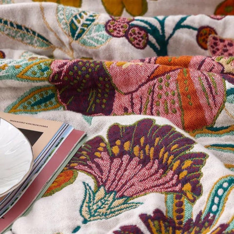 Close-up of a colorful cotton throw floral-patterned fabric with a magazine on top.