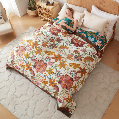 Woman lying on a bed with a elegant floral cotton blanket comforter in a bedroom setting