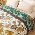 Elegant floral-patterned cotton blanket on a bed with white pillows
