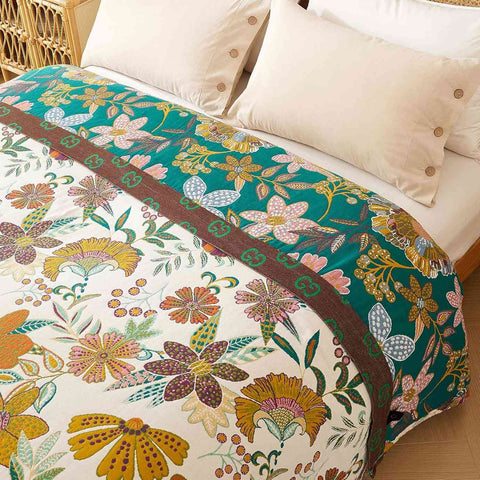 Elegant floral-patterned cotton blanket on a bed with white pillows