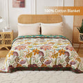 Floral patterned 100% cotton blanket on a bed with a wicker headboard.