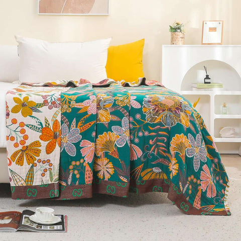 Floral patterned blanket draped over a bed in a room with a yellow pillow and white shelves.