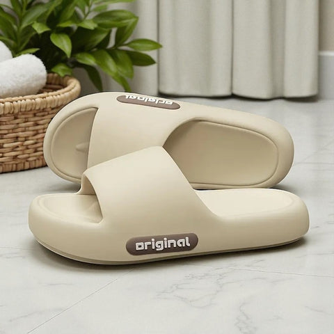Pair of beige slides with 'original' label on a light wooden floor.