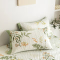 Floral pillowcases and cotton quilt detail on minimalist white bed
