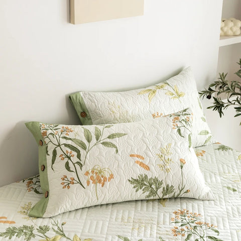 Floral pillowcases and cotton quilt detail on minimalist white bed