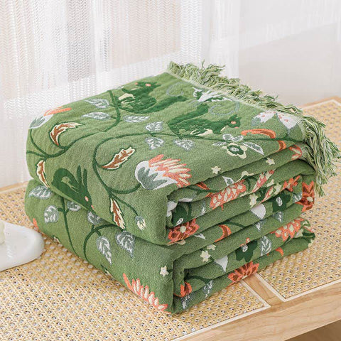 Folded green floral quilt on white bedding