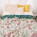 Floral Serenity cotton quilt blanket spread neatly on a bed with white and yellow pillows in a bright, minimalist bedroom.