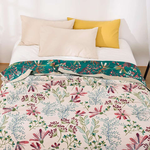 Floral Serenity cotton quilt blanket spread neatly on a bed with white and yellow pillows in a bright, minimalist bedroom.