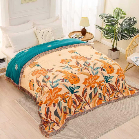 Floral patterned blanket on a bed in a bedroom with a plant and side table.