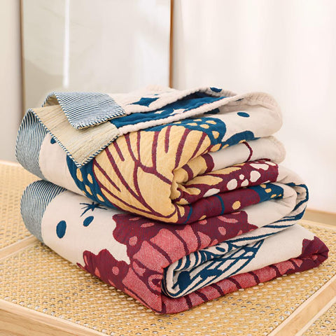 Folded butterfly cotton throw blankets stacked on a table, showcasing vibrant jacquard patterns and breathable summer-ready fabric.