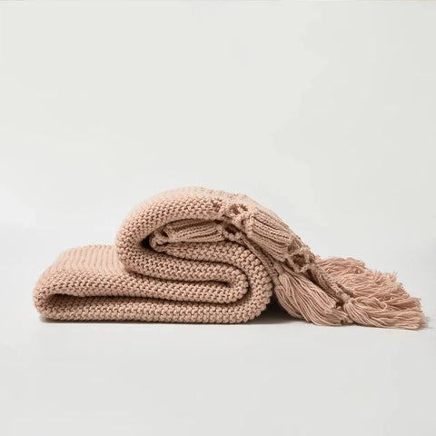 Folded Dusty Rose Nordic Knit Tassel Blanket on white floor – premium throw blanket