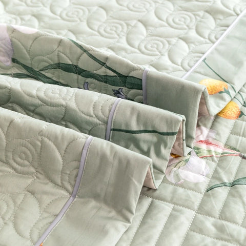 Folded green quilted cotton bedding set with botanical trim and breathable layers