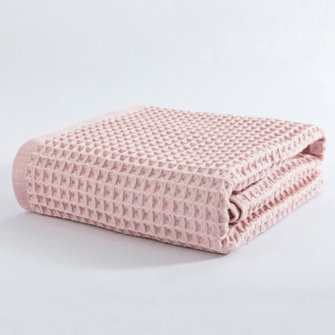 Neatly folded pink waffle cotton bath towel on white background