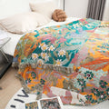 Vibrant Garden Bloom cotton throw blanket with colorful floral pattern draped over bed, showcasing soft fringed edges for cozy style.