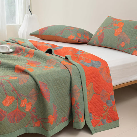 Angled close-up showing both sides of ginkgo leaf orange floral blanket fabric