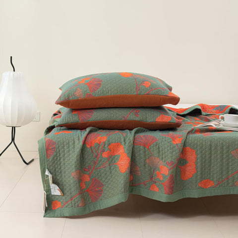 Close-up of matching pillowcases and blanket with ginkgo leaf orange floral pattern